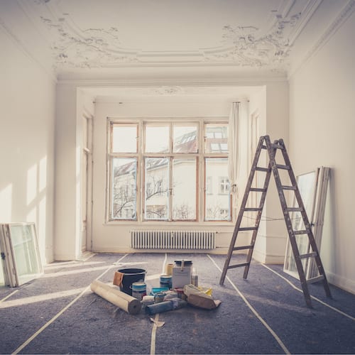 Painter preparing a bright room with paint supplies and ladder
